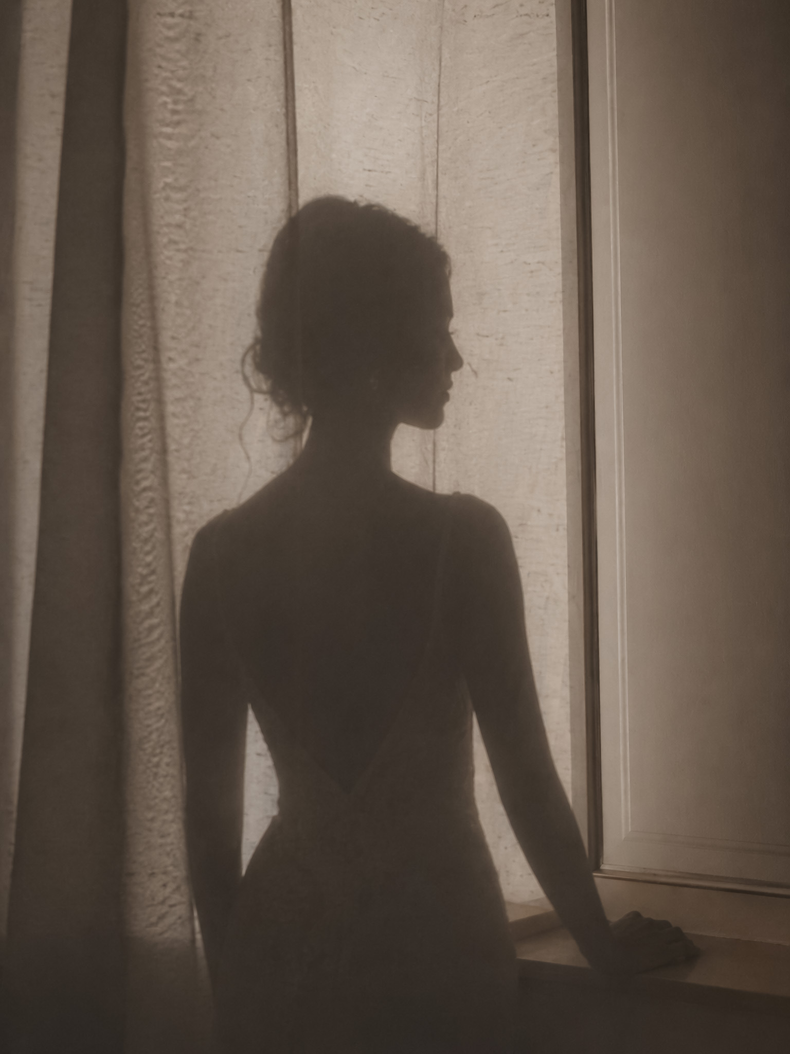 Discreet bridal silhouette near a softly lit window