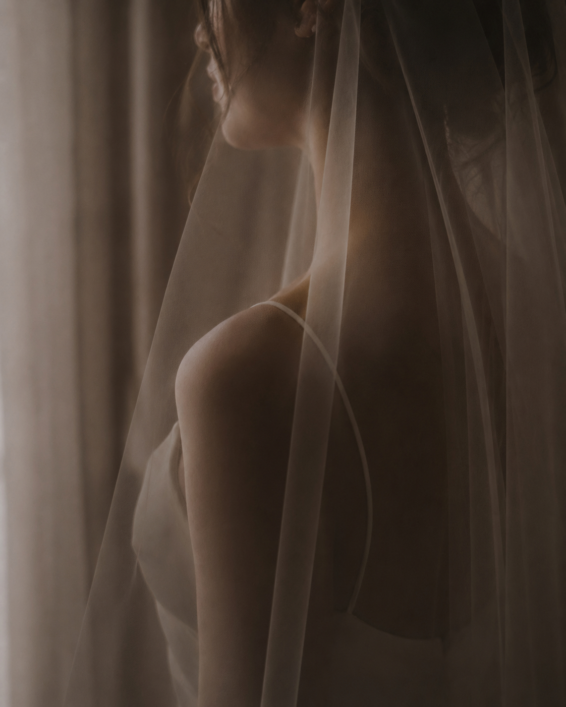 Bride partially veiled in a quiet preparatory moment