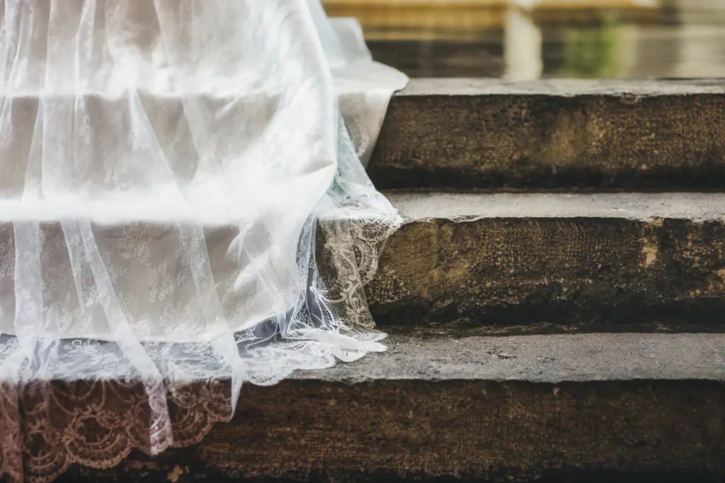 Lace wedding dress fabric resting on stone steps
