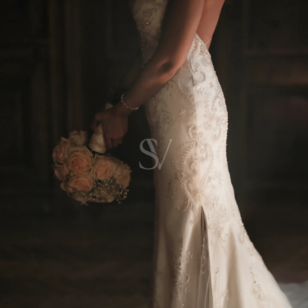 Bride holding a bouquet beside her wedding dress