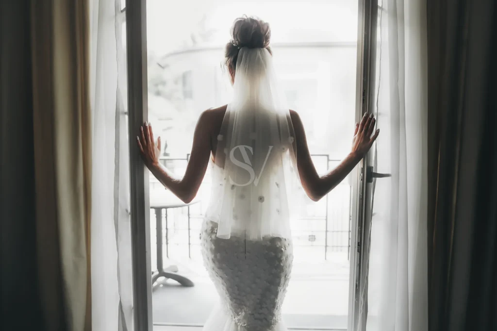 Bride standing by a window with a veil before the wedding