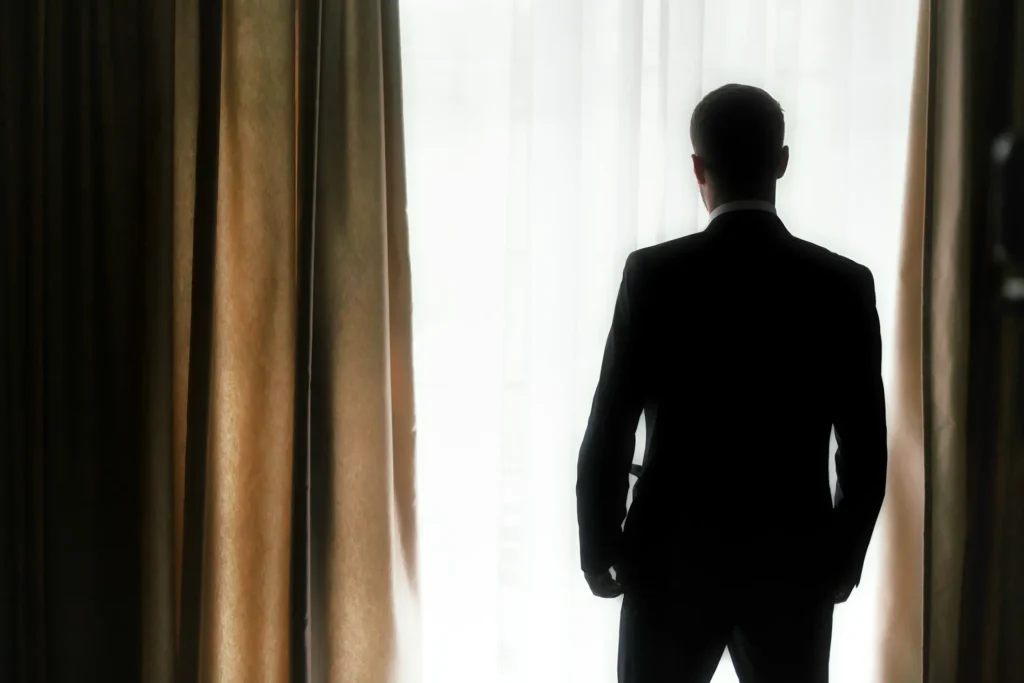 Groom standing by a window before the wedding