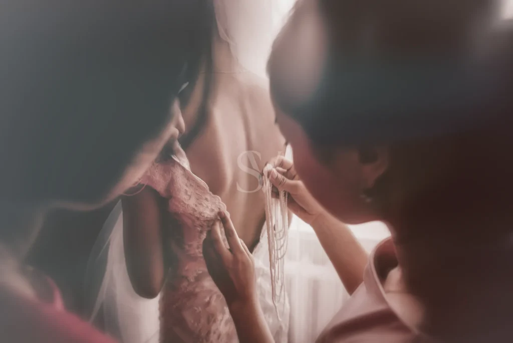 Hands fastening a necklace on the bride before the wedding
