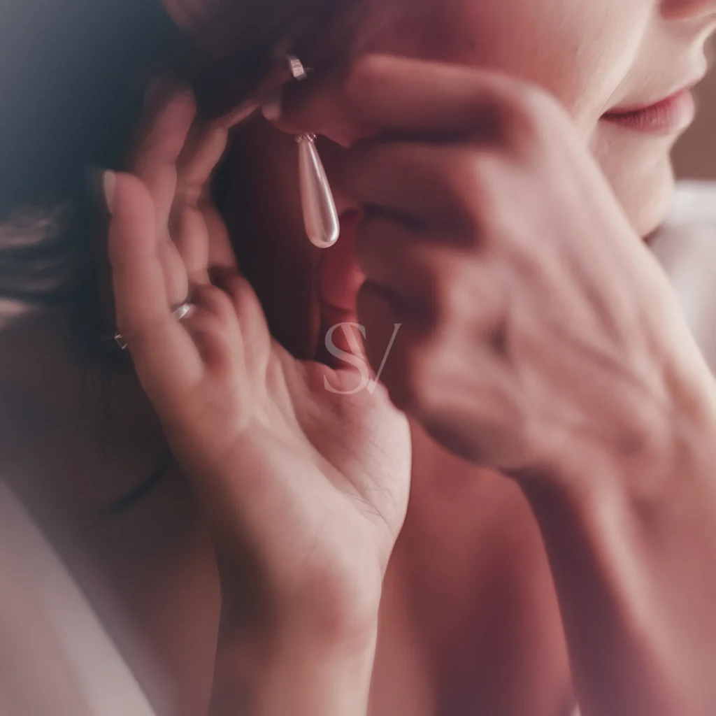 Bride putting on a pearl earring before the wedding