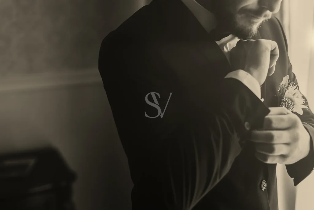 Groom adjusting his cuff with a boutonniere on his jacket