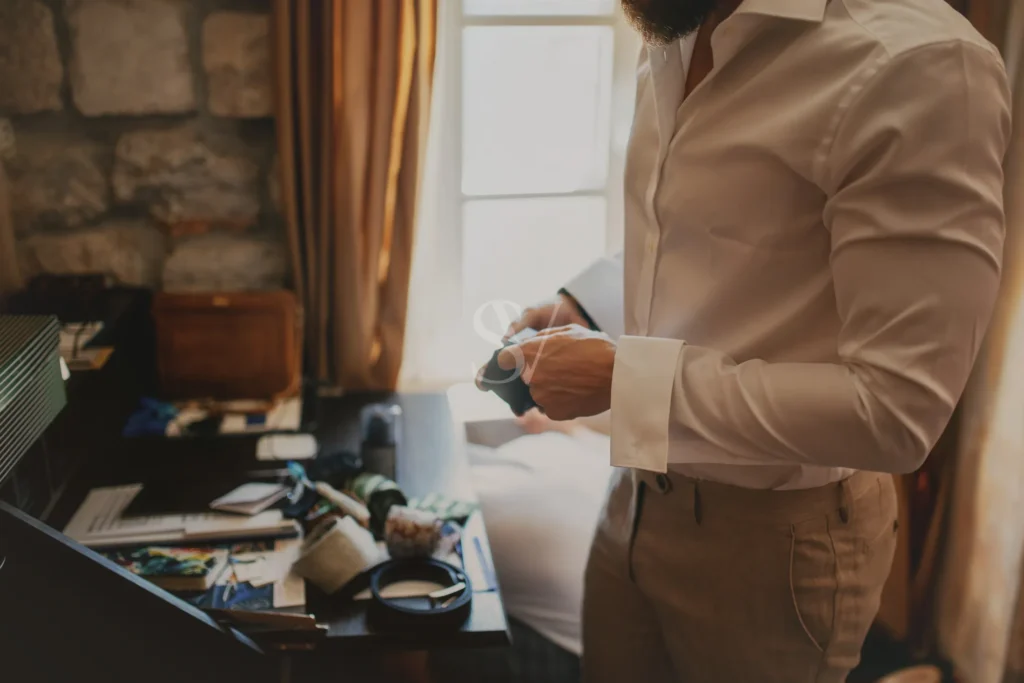 Groom fastening his shirt cuff before the wedding