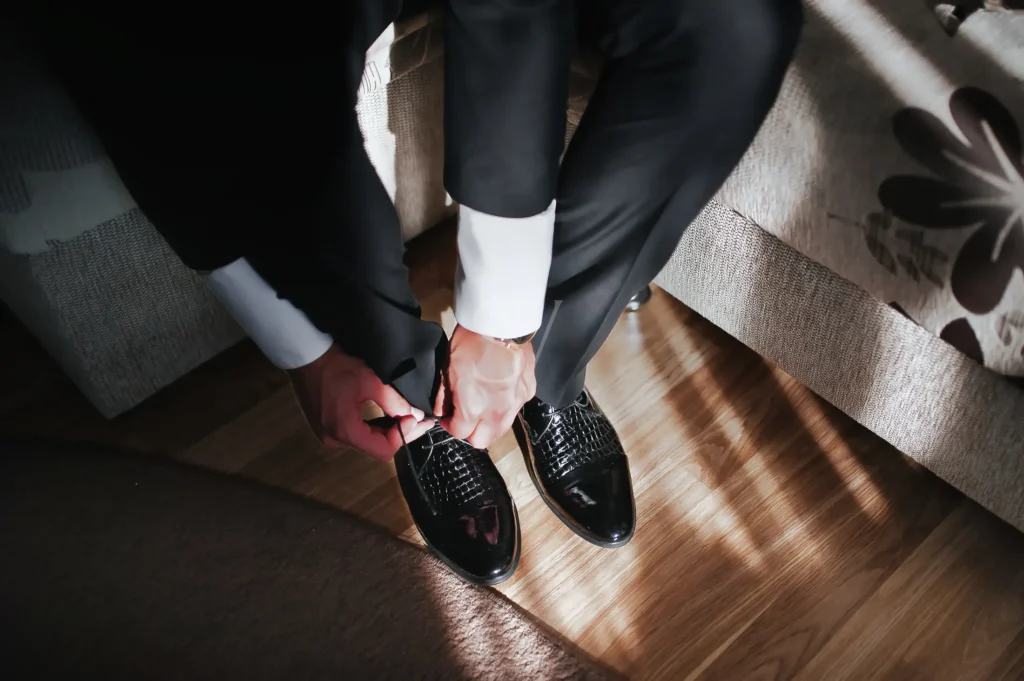 Groom tying black dress shoes before the wedding