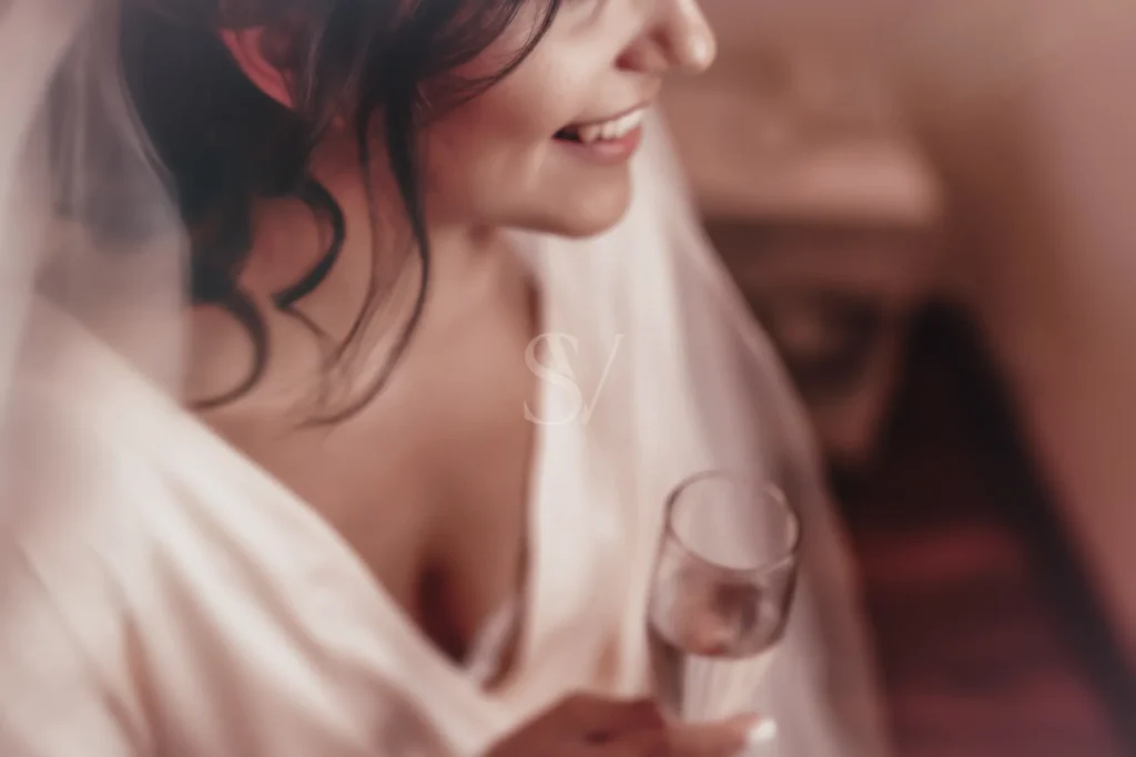 Bride holding a glass during a quiet preparation moment