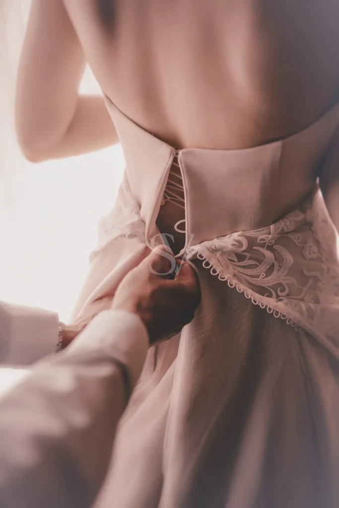 Hands fastening the back of a bride's wedding dress