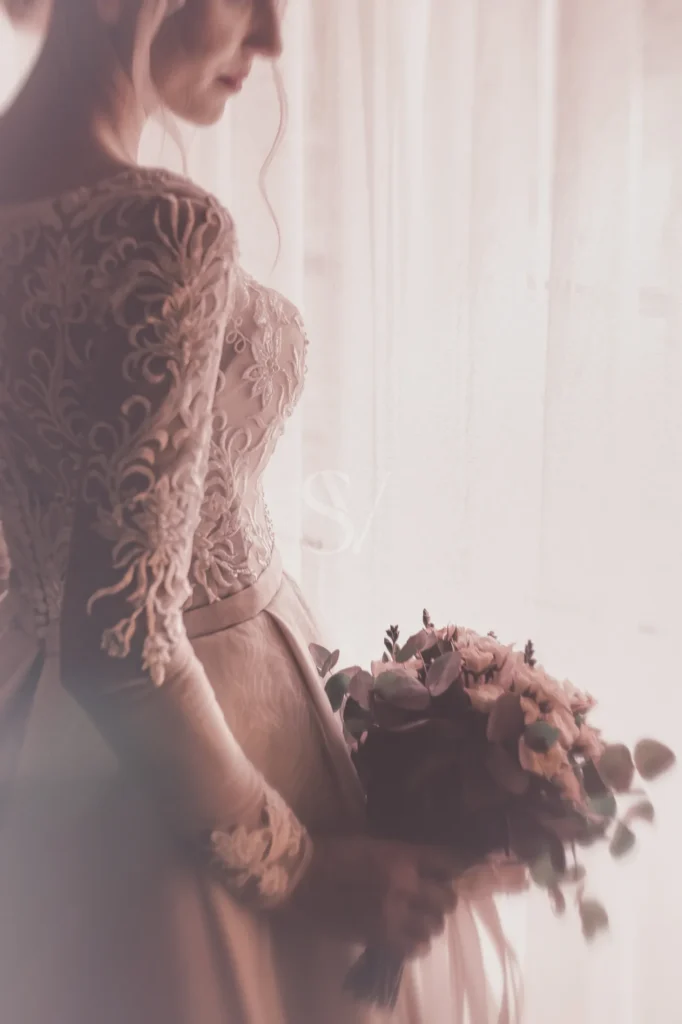 Bride holding a bouquet beside soft window light
