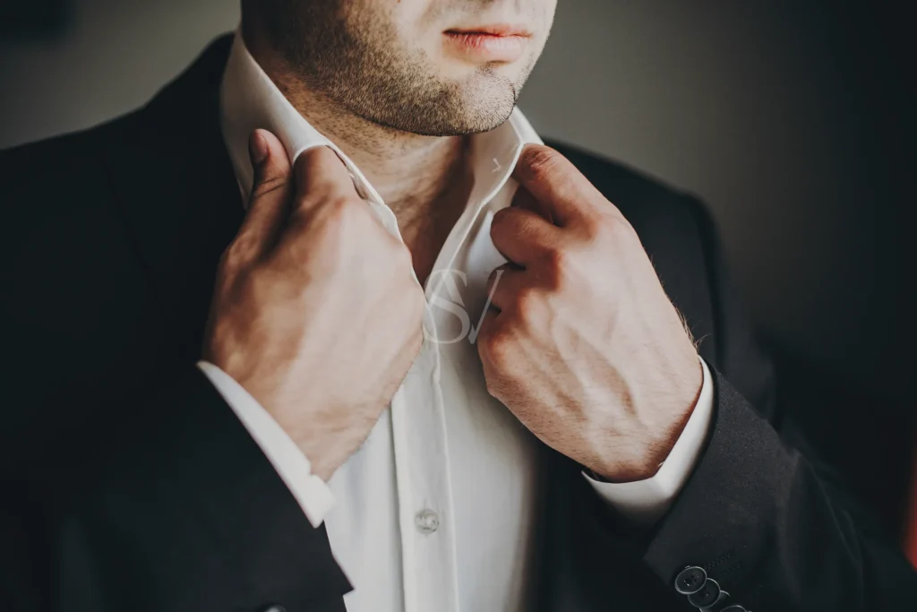 Groom adjusting his shirt collar before the wedding