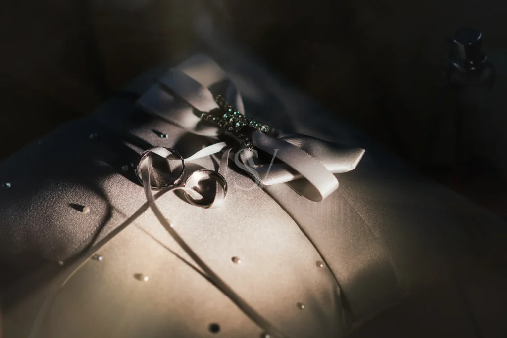 Wedding rings on a satin ring pillow in low directional light
