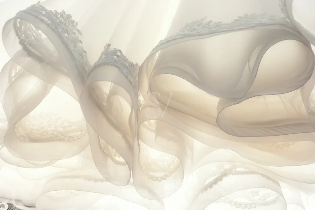 White bridal shoes beneath sheer wedding fabric