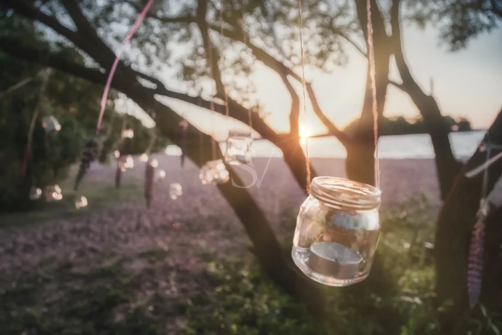 Hanging glass candle jars at an outdoor wedding reception