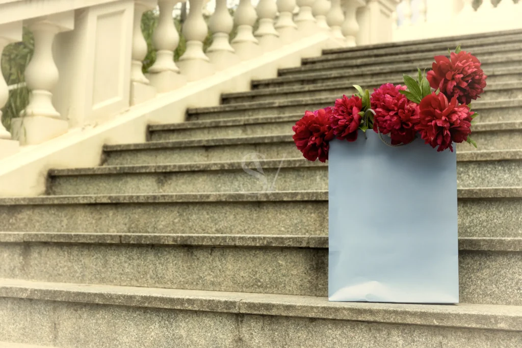 White and red floral arrangement on stone steps before a wedding reception